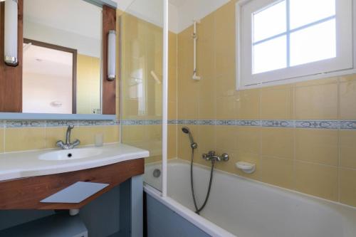 La salle de bains est pourvue d'un lavabo, d'une baignoire et d'une fenêtre. dans l'établissement Les Maisons de Port Bourgenay - maeva Home - Maison 3 pièces 6 personnes - Sélection MAE-6434, à Talmont-Saint-Hilaire