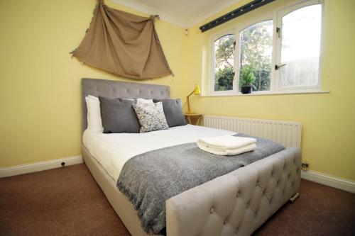 a bedroom with a large bed with two windows at Chartwell Grove (Spacious 7 BR with FREE parking) in Nottingham