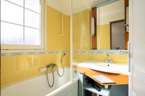 La salle de bains est pourvue de carrelage jaune, d'un lavabo et d'une douche. dans l'établissement Les Maisons de Port Bourgenay - maeva Home - Maison 3 pièces 6 personnes - Sélection MAE-6435, à Talmont-Saint-Hilaire