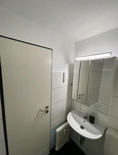ein weißes Badezimmer mit einem Waschbecken und einem Spiegel in der Unterkunft 1-Raum-Apartment Nähe Hochschule Niederrhein in Mönchengladbach