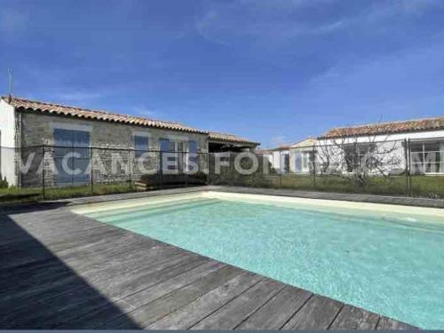 une piscine devant un immeuble dans l'établissement Villa spacieuse avec piscine privée, WiFi gratuit et jardin clos, à proximité de la mer et du centre-ville - FR-1-246A-279, à Saint-Denis-dʼOléron