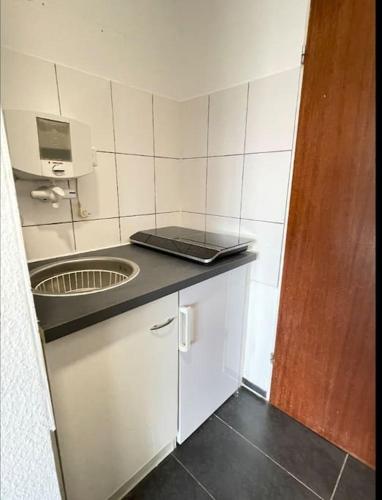 uma cozinha com um lavatório e um computador portátil no balcão em 1-Raum-Apartment Nähe Hochschule Niederrhein em Mönchengladbach