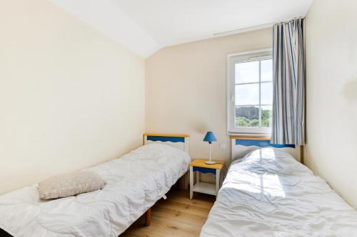 two beds in a room with a window at Les Maisons de Port Bourgenay - maeva Home - Maison 3 pièces 6 personnes - Sélection MAE-6402 in Talmont