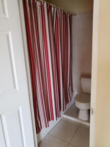 baño con cortina de ducha roja y aseo en Yacht View Apartments, en True Blue