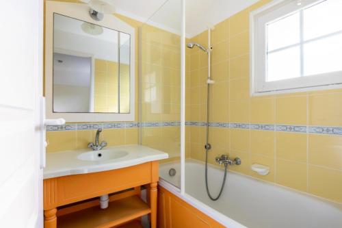une salle de bain avec un lavabo, une baignoire et un miroir dans l'établissement Les Maisons de Port Bourgenay - maeva Home - Maison 3 pièces 6 personnes - Confort MAE-6439, à Talmont-Saint-Hilaire
