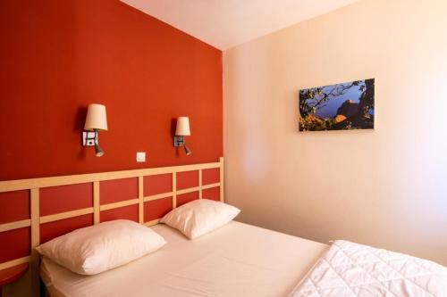 - une chambre aux murs rouges et un lit avec deux lampes dans l'établissement Résidence le Village de Cap Esterel - maeva Home - Appartement 3 Pièces 7 Personnes - Sélection MAE-6532, à Saint-Raphaël