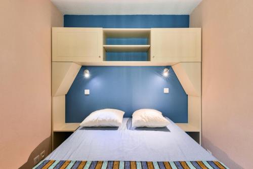 - une chambre avec un lit avec un mur bleu et deux oreillers dans l'établissement Résidence Lacanau Les Pins - maeva Home - Appartement 2 pièces 6 personnes - Prestige MAE-6659, à Lacanau