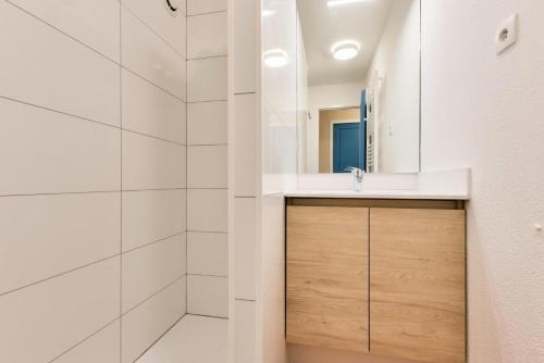 une salle de bain blanche avec un lavabo et une douche dans l'établissement Résidence Lacanau Les Pins - maeva Home - Appartement 2 pièces 6 personnes - Prestige MAE-6659, à Lacanau