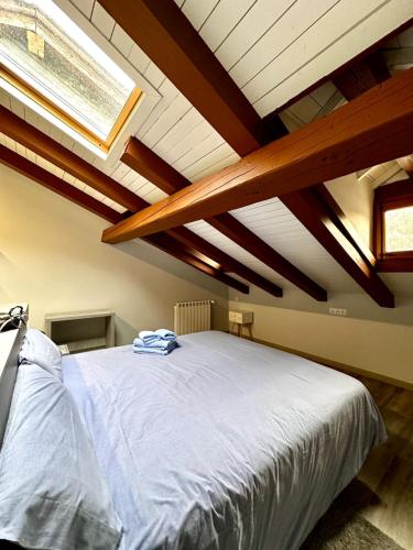 a bedroom with a large white bed with wooden beams at Casa Díaz in Os de Civís