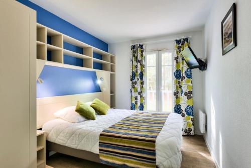 - une chambre avec des murs bleus et un lit avec des oreillers verts dans l'établissement Les Maisons de Lacanau les Pins - maeva Home - Maison 3 pièces 6 personnes - Prestige MAE-6632, à Lacanau