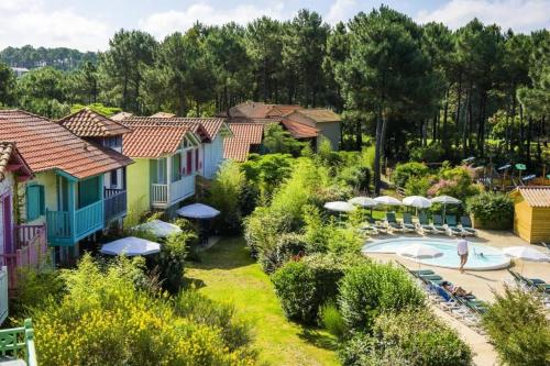 un complexe avec une piscine, des chaises et des parasols dans l'établissement Les Maisons de Lacanau les Pins - maeva Home - Maison 3 pièces 6 personnes - Sélection MAE-6658, à Lacanau