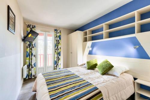 une chambre avec un lit avec un mur bleu dans l'établissement Les Maisons de Lacanau les Pins - maeva Home - Maison 3 pièces 6 personnes - Sélection MAE-6658, à Lacanau