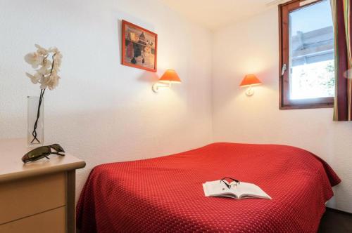 - une chambre avec un lit rouge et un livre dans l'établissement Résidence Les Fontaines Blanches - maeva Home - Appartement 2 Pièces 5 Personnes - Confort MAE-7312, à Morzine