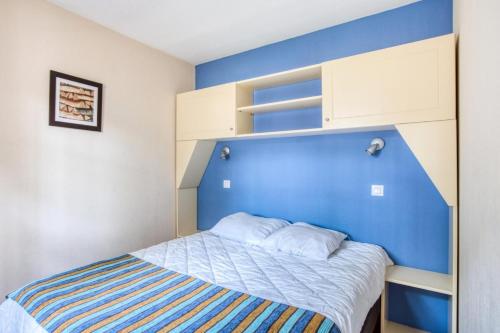 - une petite chambre avec un mur bleu et un lit dans l'établissement Résidence Lacanau Les Pins - maeva Home - Appartement 2 Pièces 5 Personnes - Sélection MAE-7323, à Lacanau