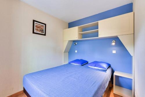 une chambre avec une tête de lit bleue et un lit dans l'établissement Résidence Lacanau Les Pins - maeva Home - Appartement 2 Pièces 5 Personnes - Prestige MAE-7327, à Lacanau