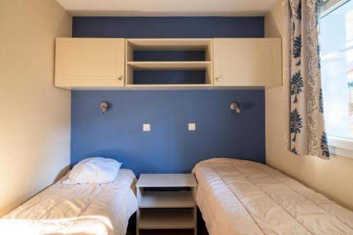 une chambre avec deux lits et un mur bleu dans l'établissement Résidence Lacanau Les Pins - maeva Home - Appartement 2 Pièces 4 Personnes - Sélection MAE-7335, à Lacanau
