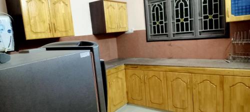 a kitchen with wooden cabinets and a refrigerator at AVAR Home syay in Virāmpattinam