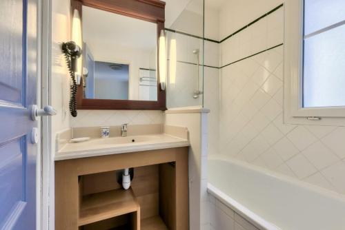une salle de bain avec un lavabo, une baignoire et un miroir dans l'établissement Les Maisons de Lacanau les Pins - maeva Home - Maison 3 pièces 6 personnes - Sélection MAE-7336, à Lacanau