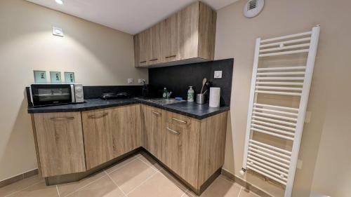 a kitchen with wooden cabinets and a microwave at Studio - Hyper Centre - Proche Gare in Verneuil d'Avre et d'Iton