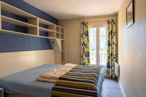 - une chambre avec un lit, des étagères et une fenêtre dans l'établissement Les Maisons de Lacanau les Pins - maeva Home - Maison 3 pièces 6 personnes - Sélection MAE-7342, à Lacanau