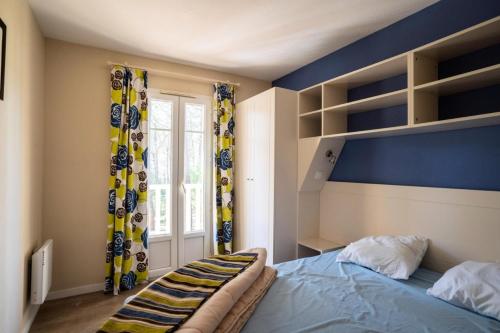 une chambre avec un lit et un mur bleu dans l'établissement Les Maisons de Lacanau les Pins - maeva Home - Maison 3 pièces 8 personnes - Sélection MAE-7343, à Lacanau