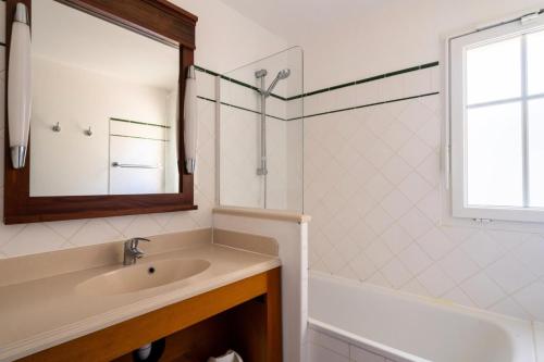 une salle de bain avec un lavabo, une baignoire et un miroir dans l'établissement Les Maisons de Lacanau les Pins - maeva Home - Maison 3 pièces 8 personnes - Sélection MAE-7343, à Lacanau