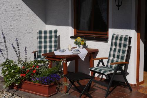 a patio with two chairs and a table and flowers at Gaestehaus Hofer in Bad Birnbach