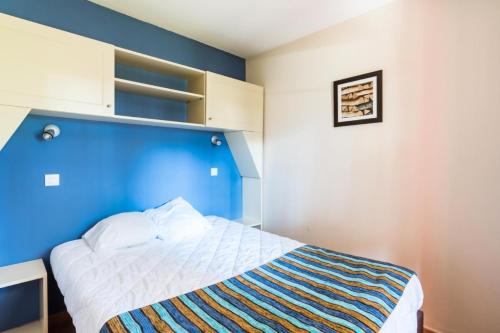 une chambre avec un mur bleu et un lit dans l'établissement Résidence Lacanau Les Pins - maeva Home - Appartement 2 Pièces 5 Personnes - Sélection MAE-7444, à Lacanau