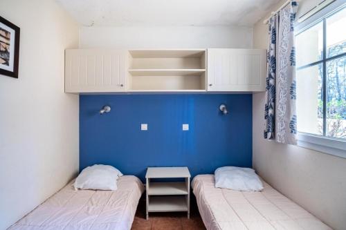 - 2 lits dans une chambre avec un mur bleu dans l'établissement Résidence Lacanau Les Pins - maeva Home - Appartement 2 Pièces 4 Personnes - Sélection MAE-7453, à Lacanau