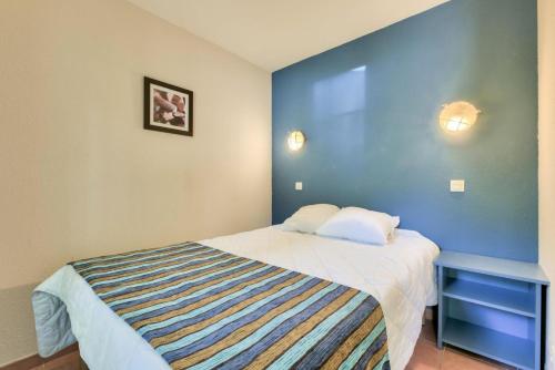 ein Schlafzimmer mit einem Bett und einer blauen Wand in der Unterkunft Résidence Lacanau Les Pins - maeva Home - Appartement 2 Pièces 5 Personnes 92 in Lacanau