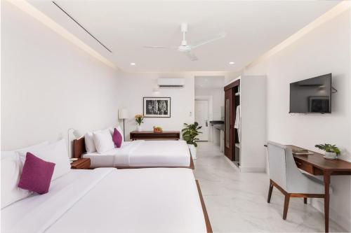a white bedroom with two beds and a desk at Elysium Suite in Siem Reap