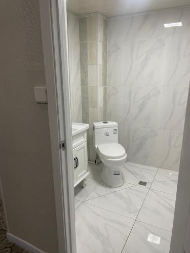 a bathroom with a toilet and white marble walls at 247 Hotel in Ulaanbaatar