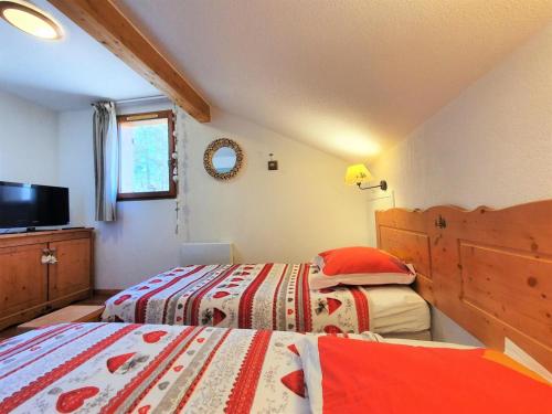 a bedroom with two beds and a tv in it at Résidence Le Hameau Du Puy - Chalets pour 6 Personnes 234 in Le Dévoluy