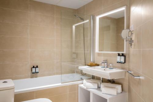 een badkamer met een wastafel, een bad en een toilet bij Occidental Mar Menor in Cartagena