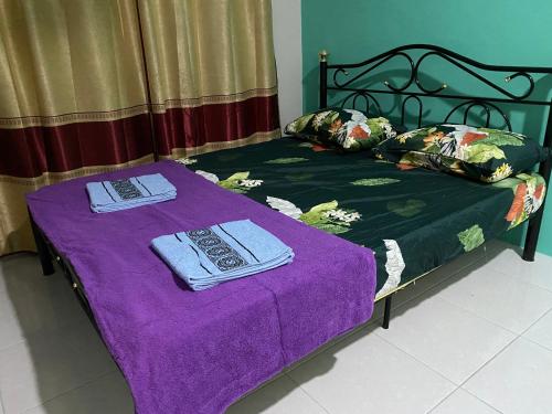 a bed with purple sheets and towels on it at The Time in Kota Samarahan