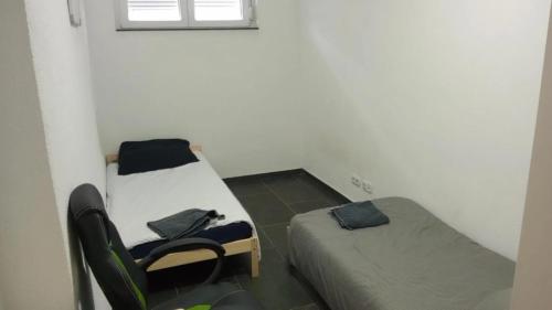a room with two beds and a chair in it at Nina Zimmer in Heilbronn Zentrum in Heilbronn