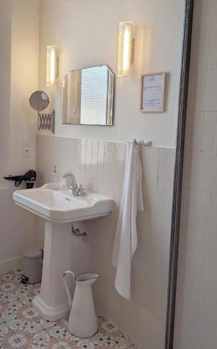 a white bathroom with a sink and a mirror at Le Couvent des Ecrevisses in Barjols