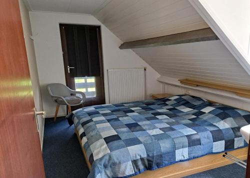 um quarto com uma cama xadrez e uma cadeira em Vakantiehuis Lauwersmeer em Lauwersoog