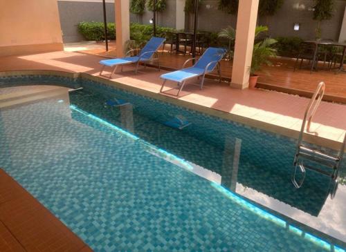 a swimming pool with two blue chairs next to it at swiss pearl continental hotel in Kano