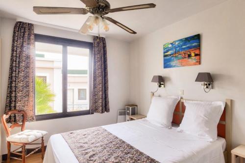 - une chambre avec un lit, un ventilateur de plafond et une fenêtre dans l'établissement Résidence Cannes Villa Francia - maeva Home - Appartement 3 pièces 6 personnes - Sélection MAE-8432, à Cannes