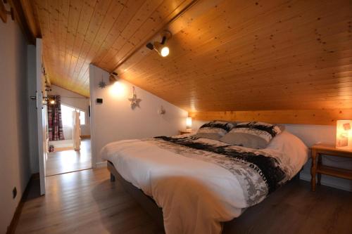 uma cama grande num quarto com tecto em madeira em Résidence La Sapiniere - 4 Pièces pour 5 Personnes 454 em Notre-Dame-de-Bellecombe