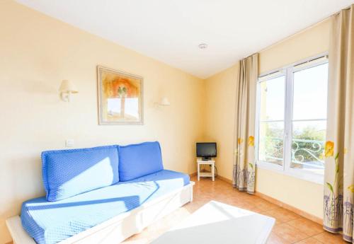 un salon avec un canapé bleu et une fenêtre dans l'établissement Résidence le Hameau des Issambres - maeva Home - 2 Pièces 7 Personnes Sélection MAE-8612, aux Issambres
