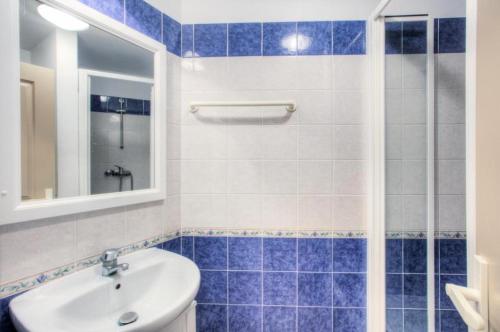 une salle de bain carrelée bleue avec un lavabo et une douche dans l'établissement Résidence le Hameau des Issambres - maeva Home - 2 Pièces 7 Personnes Sélection MAE-8612, aux Issambres