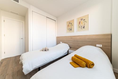 twee bedden in een slaapkamer met witte muren en houten vloeren bij Casa Cayena - Cosy & Trendy apartment near Villa Martin Golf in Orihuela