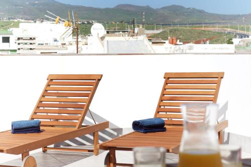 Apartamentos a 10 minutos del Aeropuerto في Carrizal: كرسيين خشبيين وطاولة مع كوب من عصير البرتقال