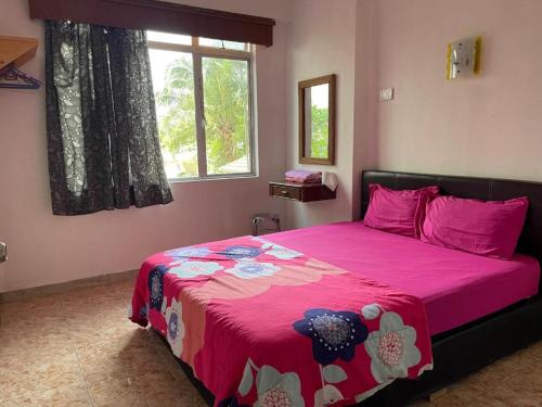 1 dormitorio con cama rosa y manta rosa en Cuti Cuti apartment Glory Beach en Port Dickson