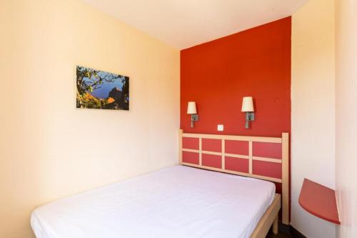 a bedroom with a bed and red walls at Résidence le Village de Cap Esterel - maeva Home - Appartement 2 Pièces 5 Personnes - Sélection MAE-8688 in Saint-Raphaël