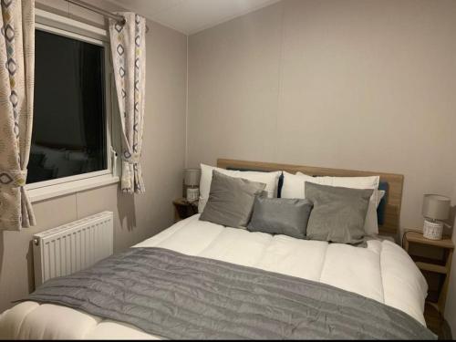 Una cama grande en un dormitorio con ventana. en Southview Holiday Park, Deluxe Caravan, en Skegness