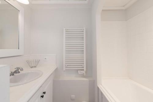 une salle de bain blanche avec un lavabo et un miroir dans l'établissement Les Bastides aux Restanques du Golfe de St Tropez - maeva Home - Appartement charmant 3 pièces 6 personnes - Sélection - super Home MAE-9584, à Grimaud