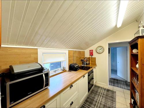 una cocina con microondas en una encimera de madera en Ameliafield Cottage, Prestwick en Prestwick